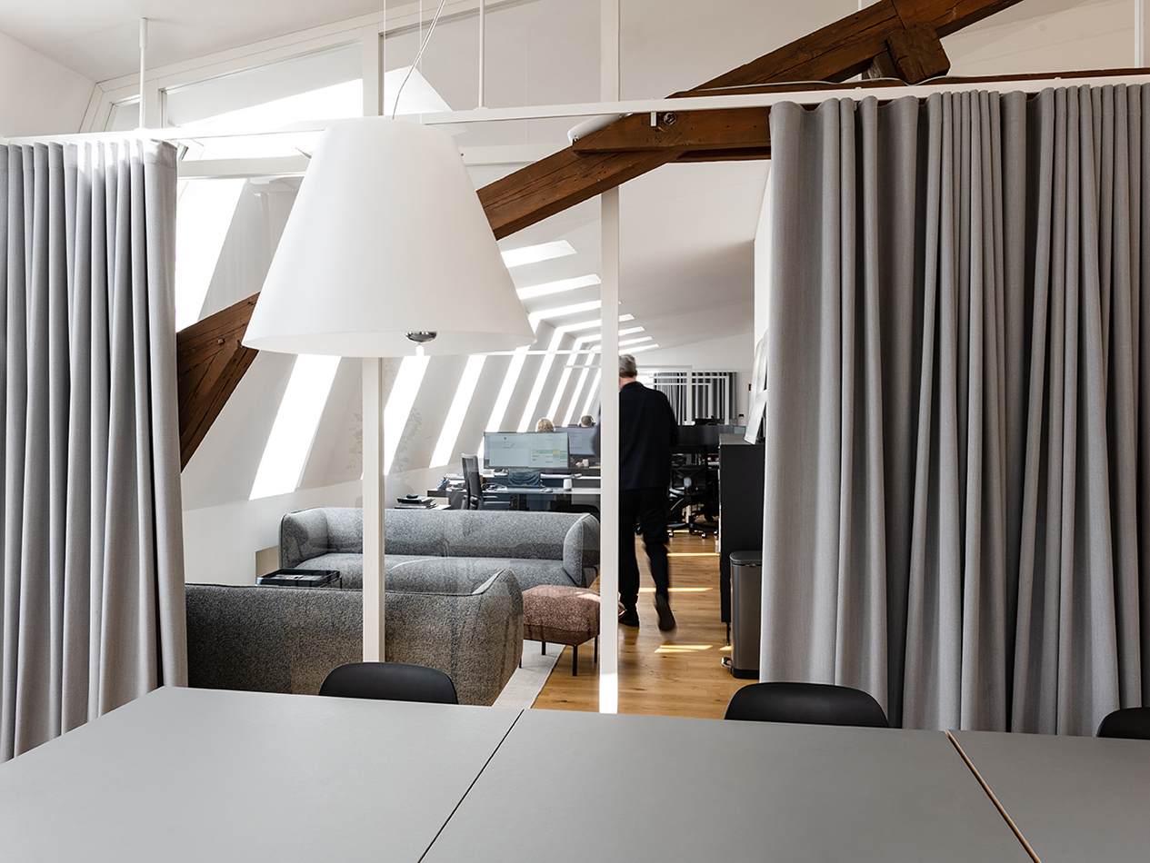 Büroräume von C.F. Møller Architects mit Holzbalken und grauen Vorhängen