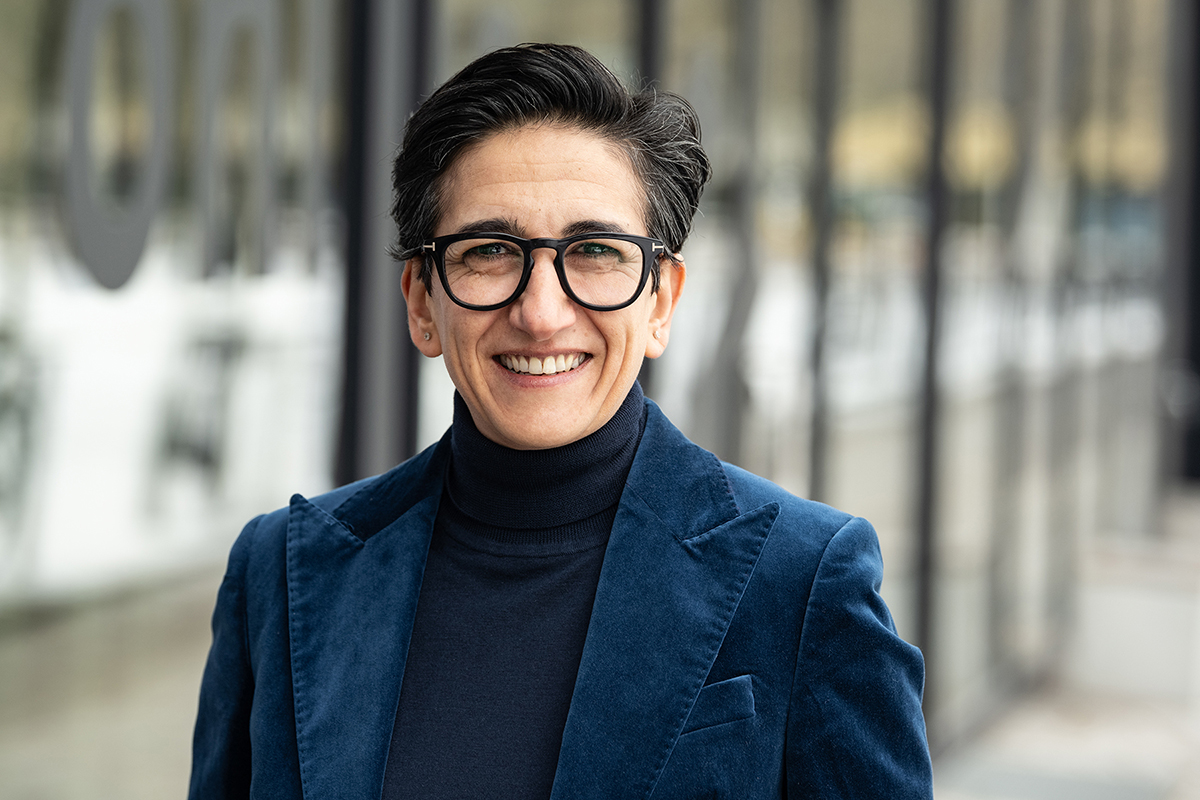 CEO Asli Kutlucan im blauen Samtblazer vor einer Glasfassade