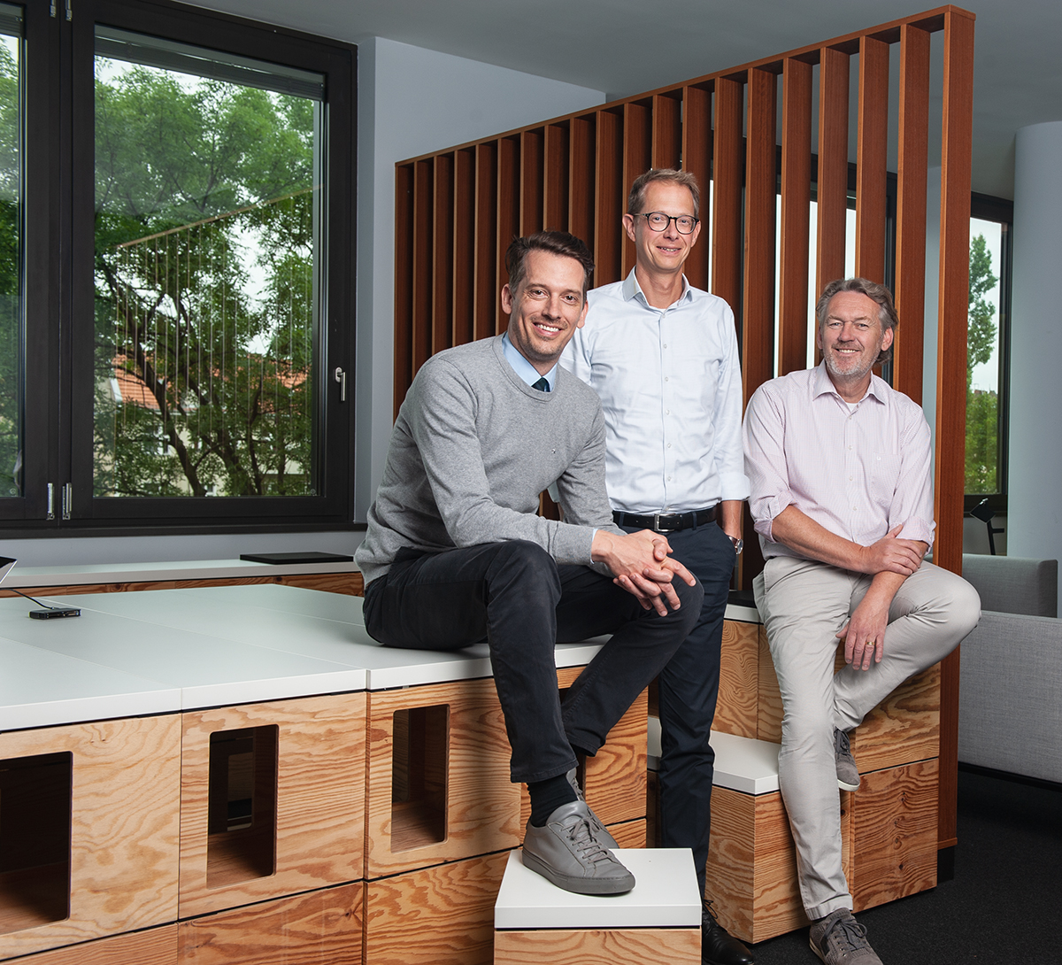 Drei Partner von CMS Hasche Sigle vor einer Holzlamellenwand