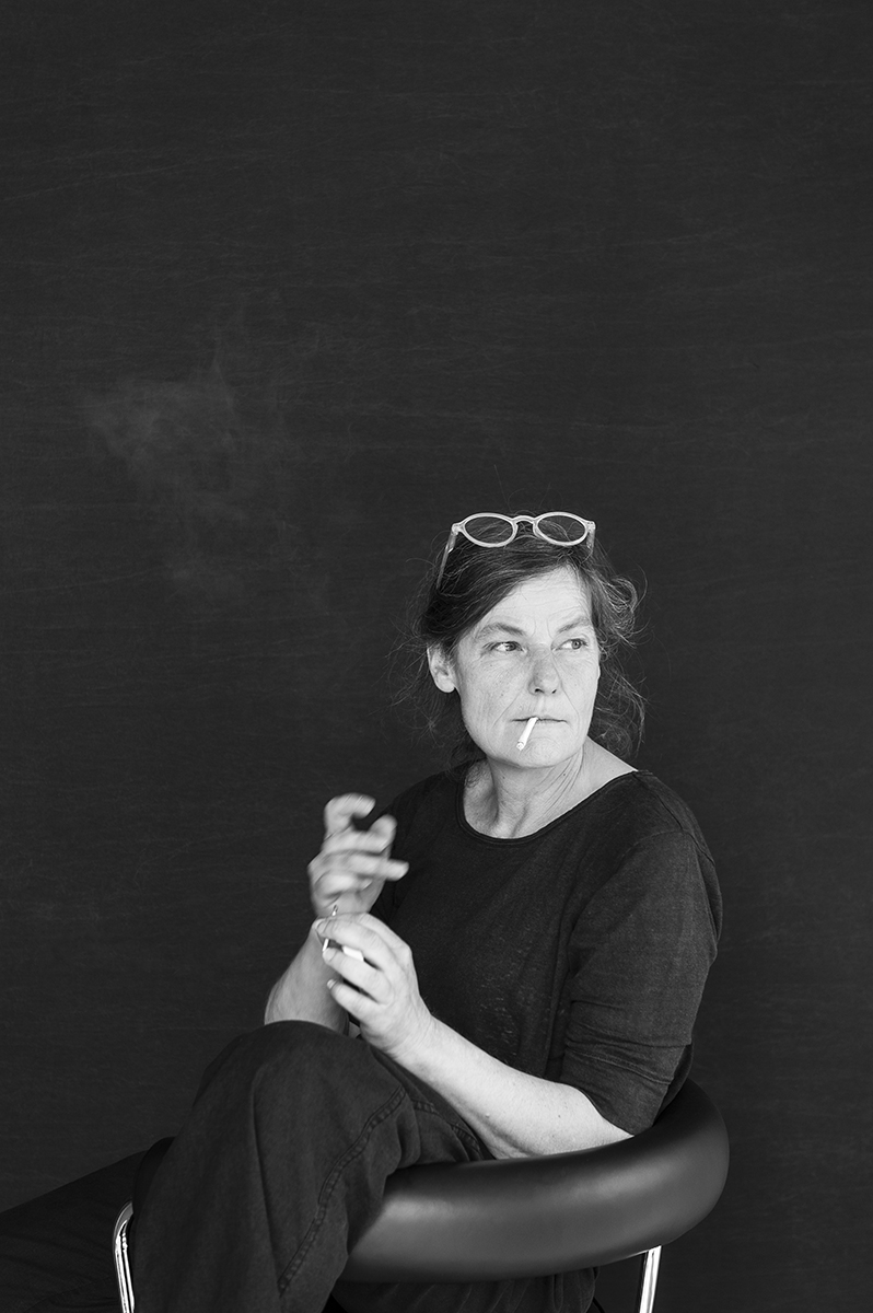Schwarz-Weiß-Porträt von Anna Weber mit Brille im Haar und Zigarre in der Hand, sitzend auf einem Drehstuhl